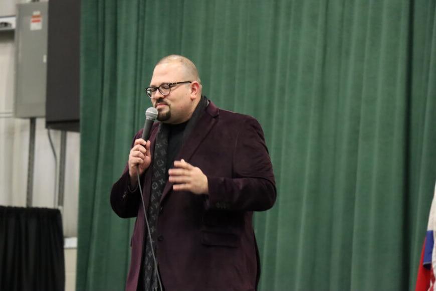 male performing with a microphone on stage